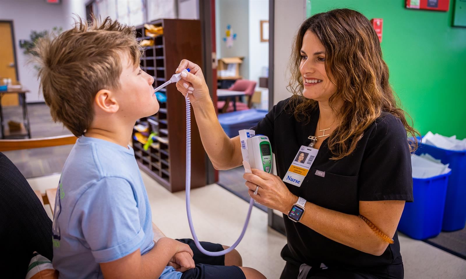 A nurse takes a student's temperature